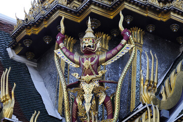 Statue de porteur au palais impérial de Bangkok. Personnage au visage de dragon ou singe à longues dents et grandes oreilles, couleur lie de vin et vêtu d'une armure dorée.
