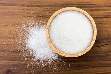 Closeup Monosodium glutamate ( MSG ) in wooden bowl isolated on rustic wooden table background. Top view. Flat lay.