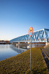 No swimming sign by Odra River in Szczecin sunset, Brdowski Bridge in background, Poland.