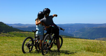 Obraz premium mountain biker, two children with bike and look at the beautiful scenery