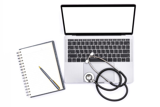 Mockup image of laptop computer with blank screen, medical stethoscope, empty notebook and pen isolated on white office desk. e health, telehealth, telemedicine or medical network concept. Top view.