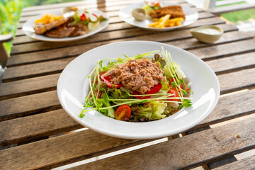 Restaurant serving food. Tuna salad in a plate on a table in a summer cafe