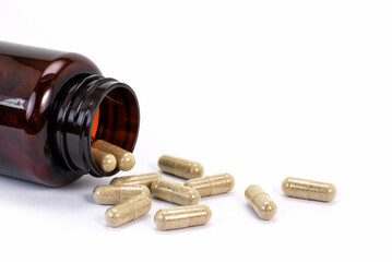 Closeup herbal capsules pill in brown glass bottle isolated on old wood table background.