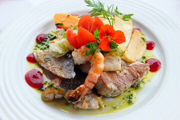 Delicious fish dish from traditional cuisine of Madeira island - grilled fillets of ocean codfish served with shrimps, shells, mussels and celery puree