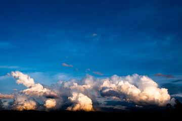 Background of clear blue sky on the upper part and dramatic cumulonimbus clouds on the lower part with rays of light. Clouds over the sky