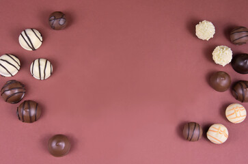 Chocolate pralines frame top view stock images. Chocolate candies on a brown background. Chocolate...