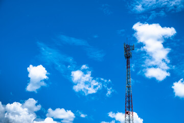 Obraz premium Telecommunication tower against clear blue sky with scattered cumulus white clouds. 