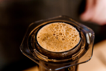 Coffee aeropress creams close-up. Alternative coffee brewing method. Aeropress device on the table. Advert for social networks of restaurants, cafe.