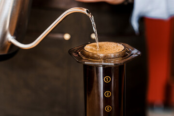 Aeropress coffee close up alternative making by barista in the cafe. Scandinavian coffee brewing...