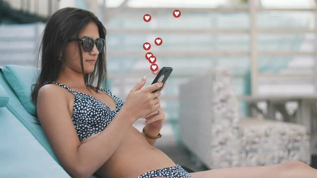 Beautiful girl in bikini and sunglasses sitting on chaise-long on a sea resort and getting a lot of likes from social networks. User interface animation
