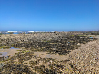 Sea waves breaking on rocks in Esposende, Portugal. Sea, beach boulders, pebble shore and waves in the morning.