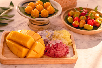Thai style tropical dessert, Yellow mango eat with Three color of Glutinous rice from natural organic, Selective focus, Two types of desserts and Nature Thai kitchen style background with day light.