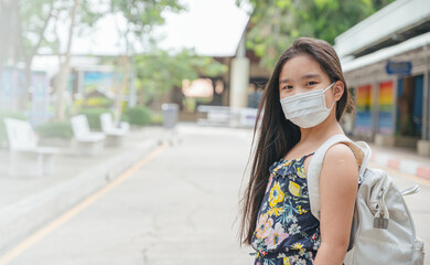 Fototapeta premium Back to school. asian child girl wearing face mask with backpack going to school .Covid-19 coronavirus pandemic.New normal lifestyle.Education concept.