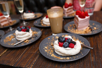 Sweet cakes with summer berries on a wooden table. Party, sweet table. Summer offer desserts in the restaurant.
