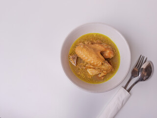 Chicken braised in coconut milk with turmeric. Indonesian food called Opor Ayam. Signature dish for Eid Holiday. Isolated in white background.