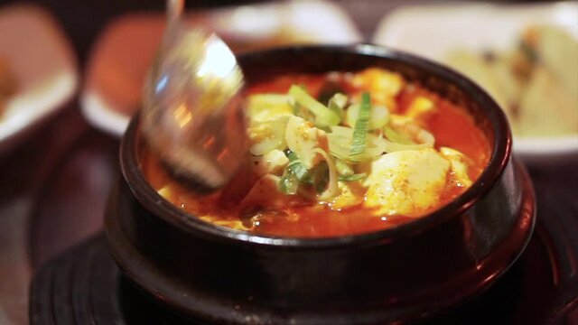 Eating Korean tofu stew with side dishes