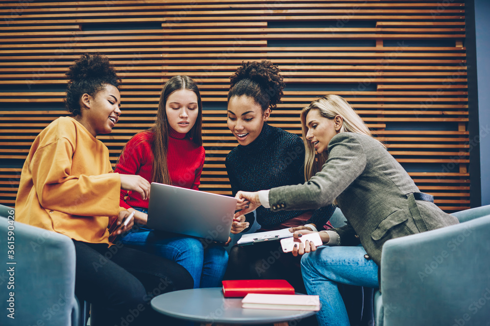 Poster cheerful multiracial females communicating with each other choosing items for shopping in web store 