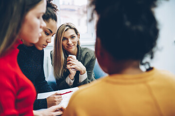 Cropped image of female multiracial crew of designers cooperating on productive job, positive blonde girl listening to colleagues idea during brainstorming session and communication on meeting