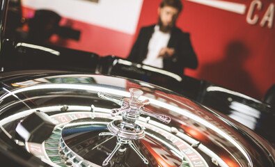 young man in a modern black suit stands next to a roulette machine and waits impatiently for a win