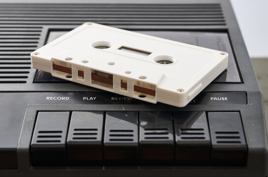 White audio cassette without markings on a black tape player. Close-up shot
