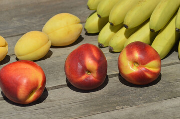 
bananas, nectarines and peaches are on a wooden table