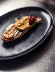 French baguette with hot Camembert cheese with jam in black plate