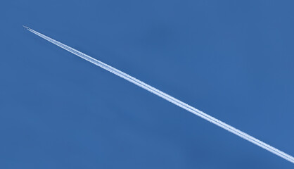 white trail of an airplane on the blue sky