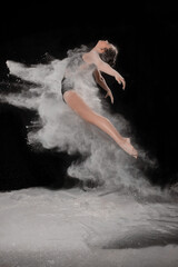 Obraz premium Girl dansing with flour on black background one person