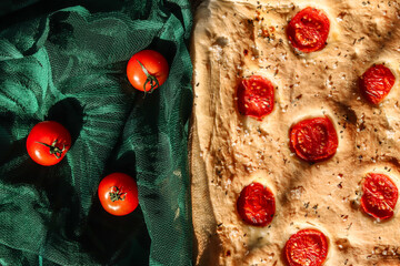 Focaccia italian bread with cherry tomatoes on a green guipure lace cloth.