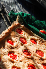 Focaccia homemaade italian bread baked with sliced cherry tomatoes, sea salt and rosemary herbs