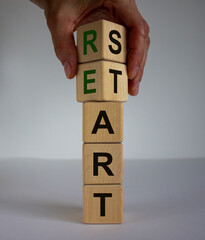 Concept word 'restart' on cubes on a beautiful wooden table. Male hand. White background. Business...