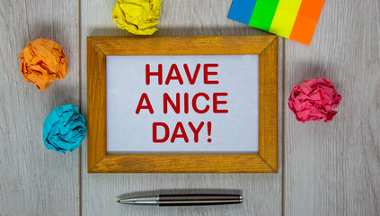 Wooden frame with inscription 'have a nice day' on beautiful wooden table, colored paper, metalic pen. Concept.