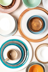 Many different ceramic plates and bowls on a light background, top view.  Different tableware. Empty colorful plates flat lay