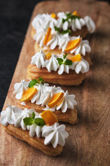 Obraz na płótnie Canvas Choux pastry. Protein cream eclairs garnished with mandarin and mint.