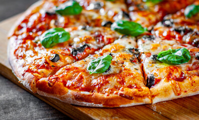 sliced Pizza with Mozzarella cheese, Tomatoes, pepper, olive, Spices and Fresh Basil. Italian pizza. Pizza Margherita or Margarita on wooden table background