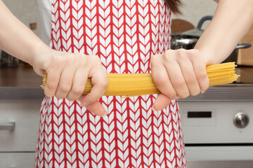 Female hands break spaghetti into pieces