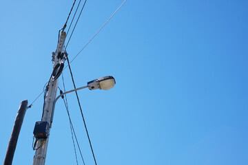 Naklejka premium Street lamp with electric lines on a blue sky