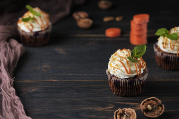 Carrot cupcakes stuffed with caramel and walnuts. Cupcakes with cream cheese cream and icing sugar. The dessert is decorated with mint and caramel.