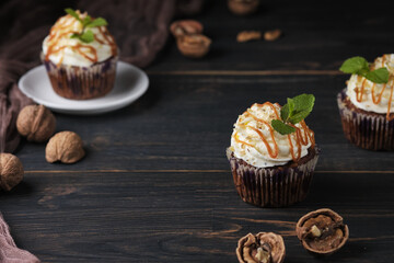 Carrot cupcakes stuffed with caramel and walnuts. Cupcakes with cream cheese cream and icing sugar. The dessert is decorated with mint and caramel.