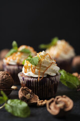 Carrot cupcakes stuffed with caramel and walnuts. Cupcakes with cream cheese cream and icing sugar. The dessert is decorated with mint and caramel.