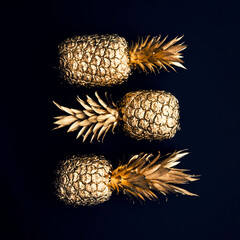 Flat lay tropical gold pineapples on a dark background