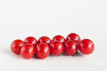 Cherry tomatoes on a branch on a light background