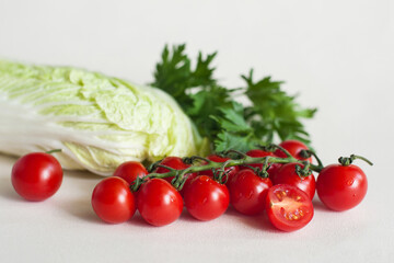 Vegetables cherry tomatoes with a twig, Peking cabbage and greens on a light background
