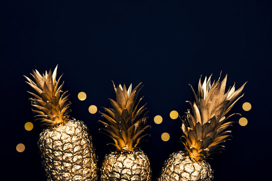 Flat lay tropical gold pineapple and confetti on a dark background