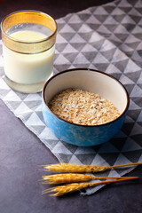 high angle view of uncooked oats flakes and milk on black background 