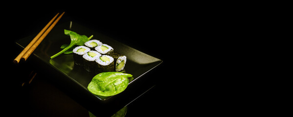 Sushi Plate With Green Baby Spinach And Sticks On a Black Background