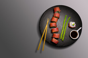 Sushi Tuna Rolls On a Black Stone With Soy Sauce And Green Asparagus