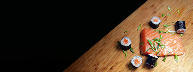 Top View of Maki Salmon Sushi On Wood Cutting Board With a Black Background