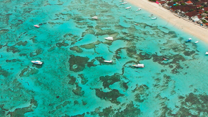 Sea reefs off the coast of the village of Lembongan with boats on the island of Nusa Lembongan. Indonesia. Aerial view.