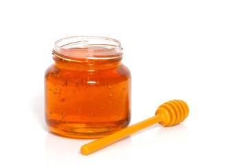 golden bee honey in a glass jar and honey dipper